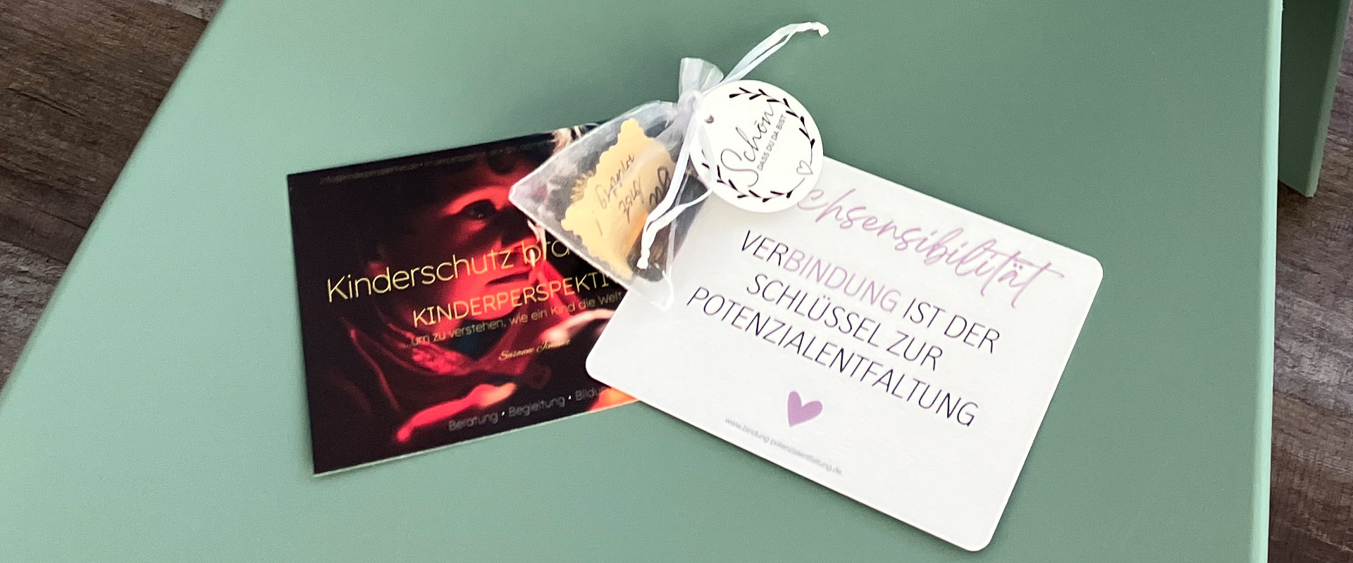 Broschüre zu Kinderschutz und eine Karte mit dem Aufdruck Beziehungssensibilität auf grünem Stuhl.